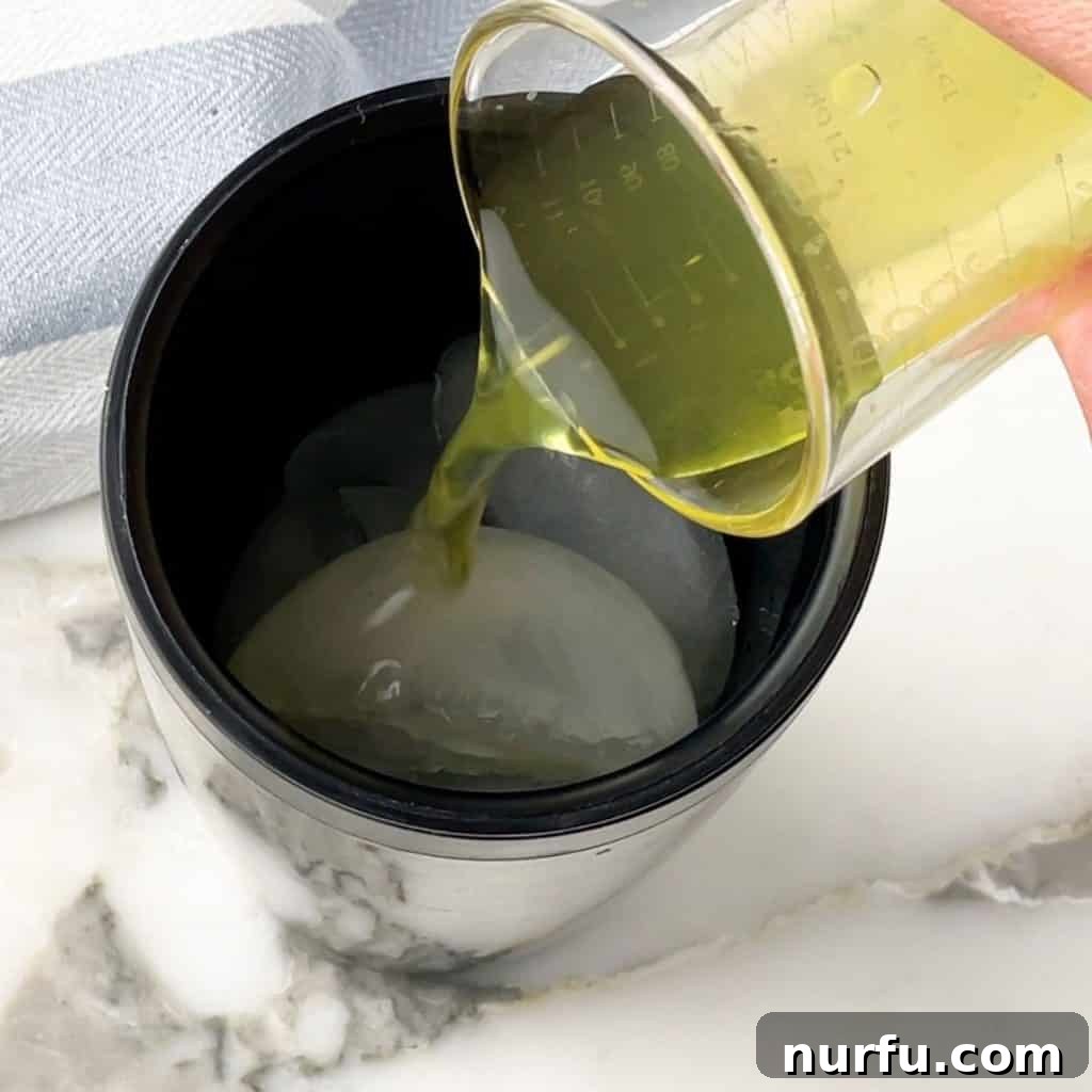 Pickle juice being poured into a cocktail shaker with ice.