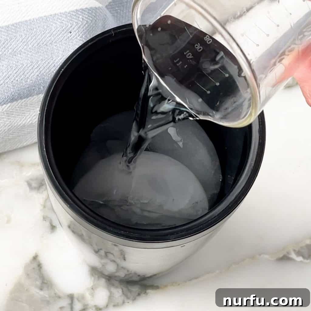 Vodka being poured into a cocktail shaker with ice and pickle juice.