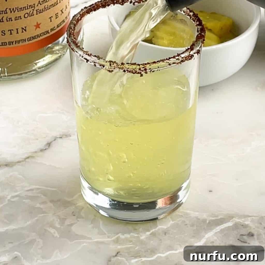 Green juice pouring into a shot glass, ready to be served.
