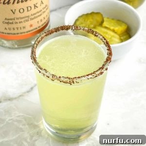 Shot glass with green liquid and bowl of pickles.
