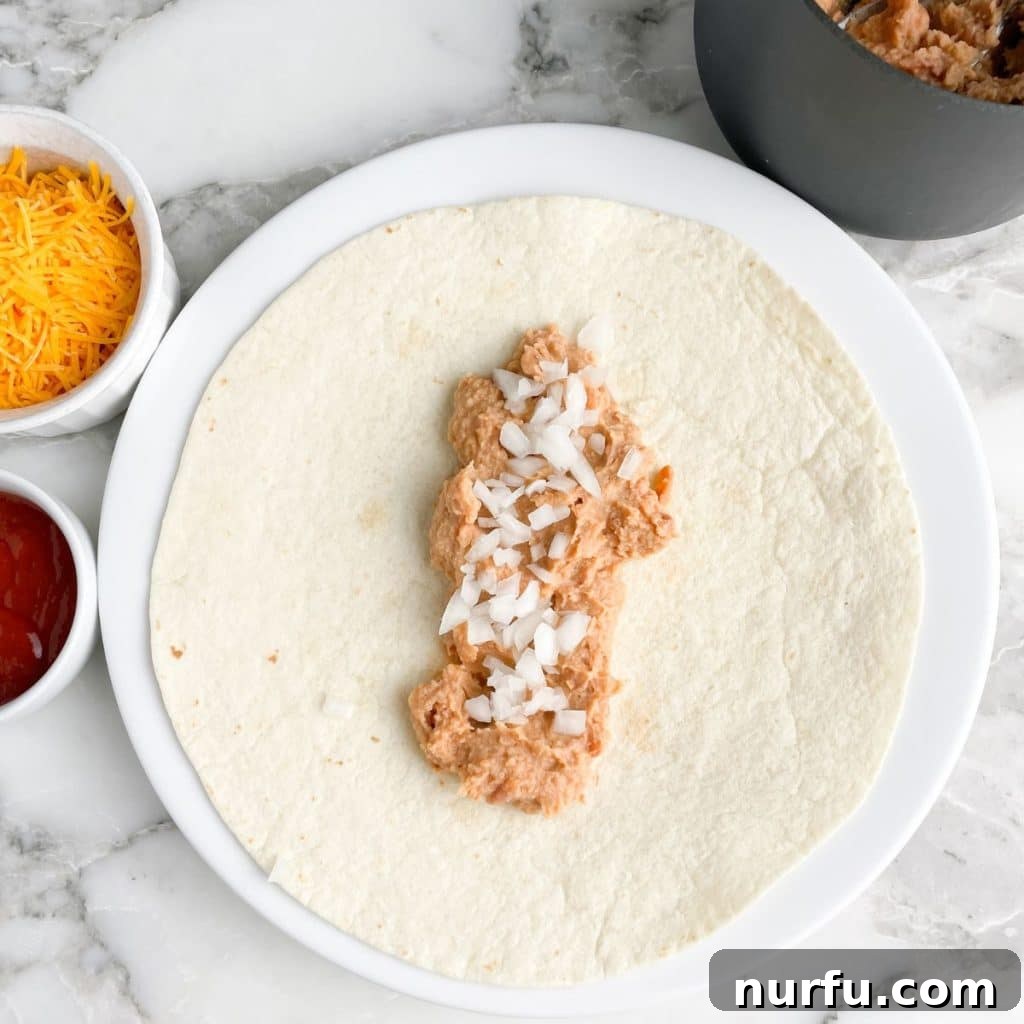 Recreate the Iconic Taco Bell Bean Burrito at Home 4 A warmed flour tortilla topped with a generous spread of refried beans and a sprinkle of finely diced onion, ready for the next ingredients.