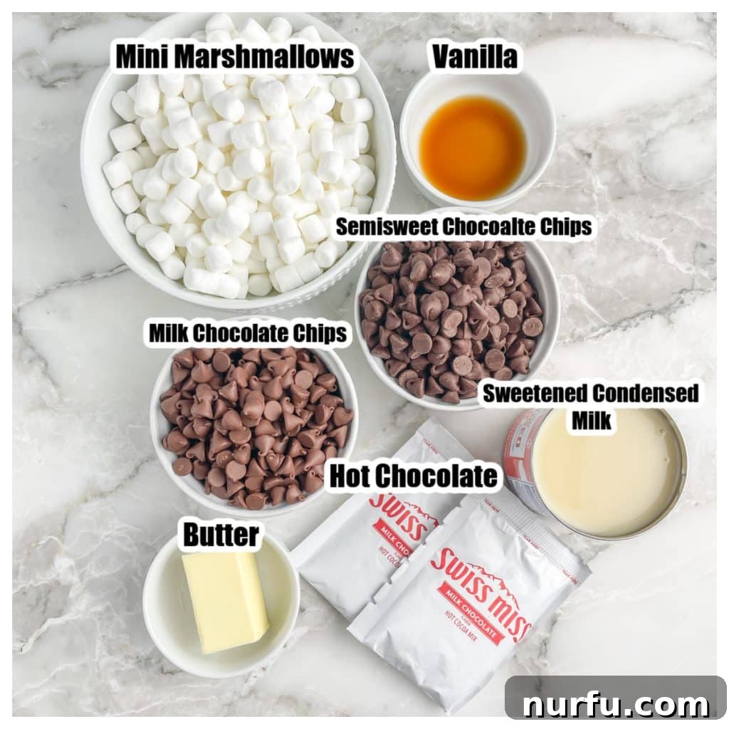 An array of fresh ingredients for hot chocolate fudge: a bowl of marshmallows, mixed chocolate chips, butter, vanilla extract, a can of sweetened condensed milk, and several hot chocolate mix packets.