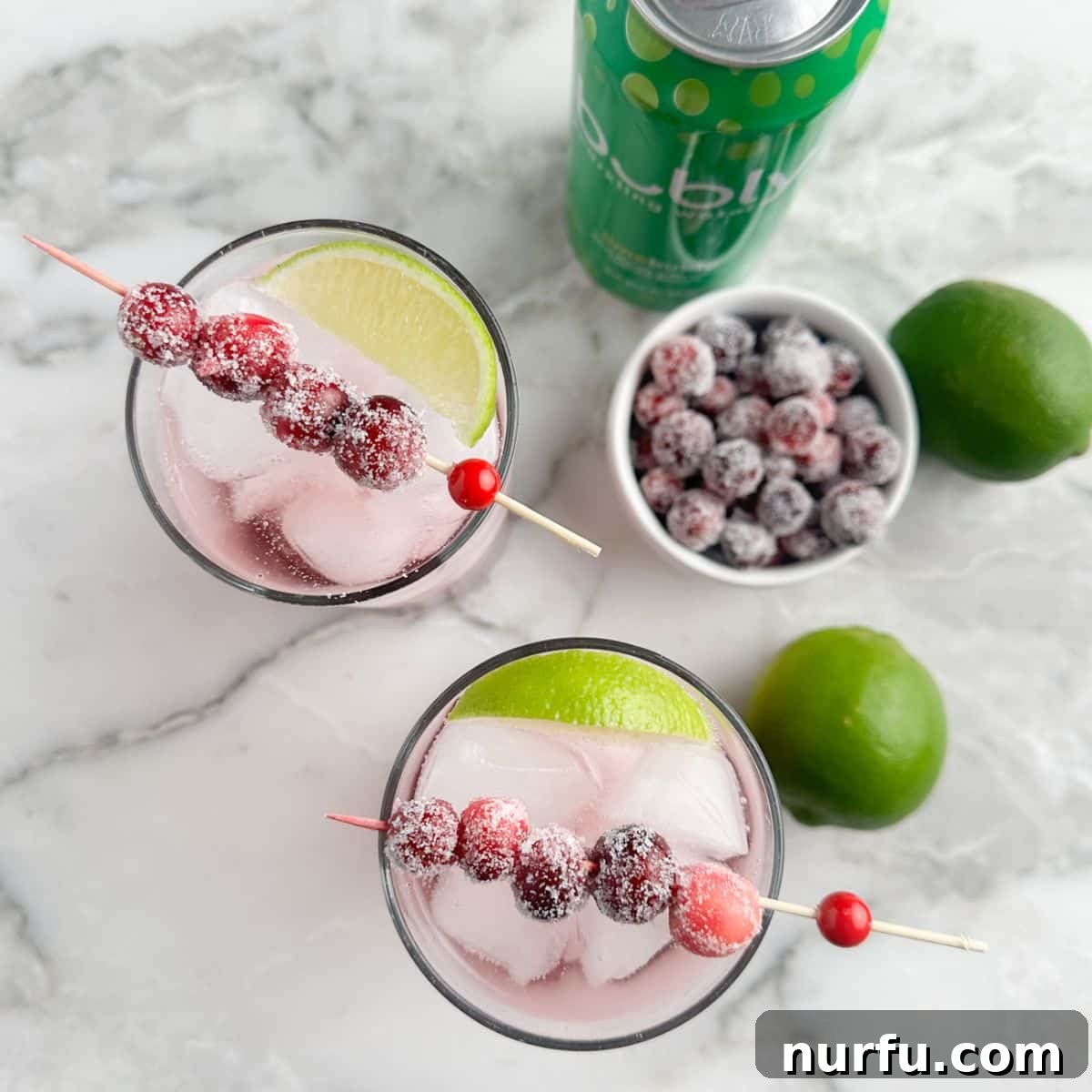 Crimson Citrus Sparkle 8 Glasses with cranberry mocktail, limes, and sugared cranberries.