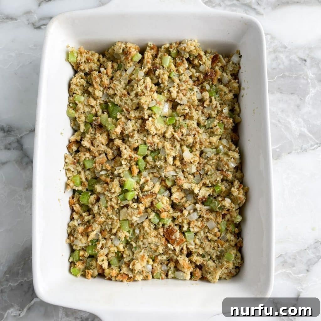 Crispy Oven Baked Stove Top Stuffing 6 A white casserole dish filled with baked stuffing, showcasing a golden, slightly crispy top, fresh out of the oven.