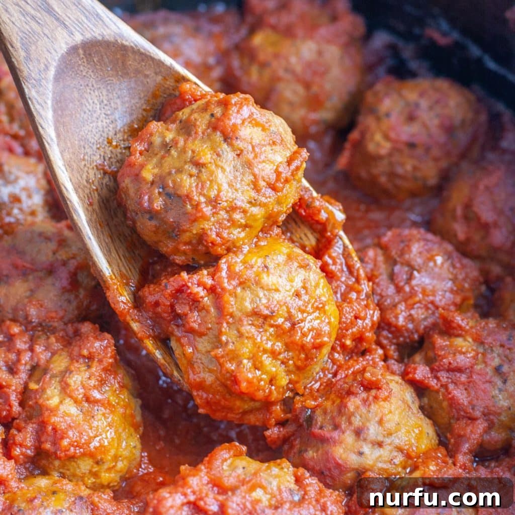 Crockpot Frozen Meatballs: Your Guide to Perfect Timing 2 Wooden spoon with meatballs and red sauce.