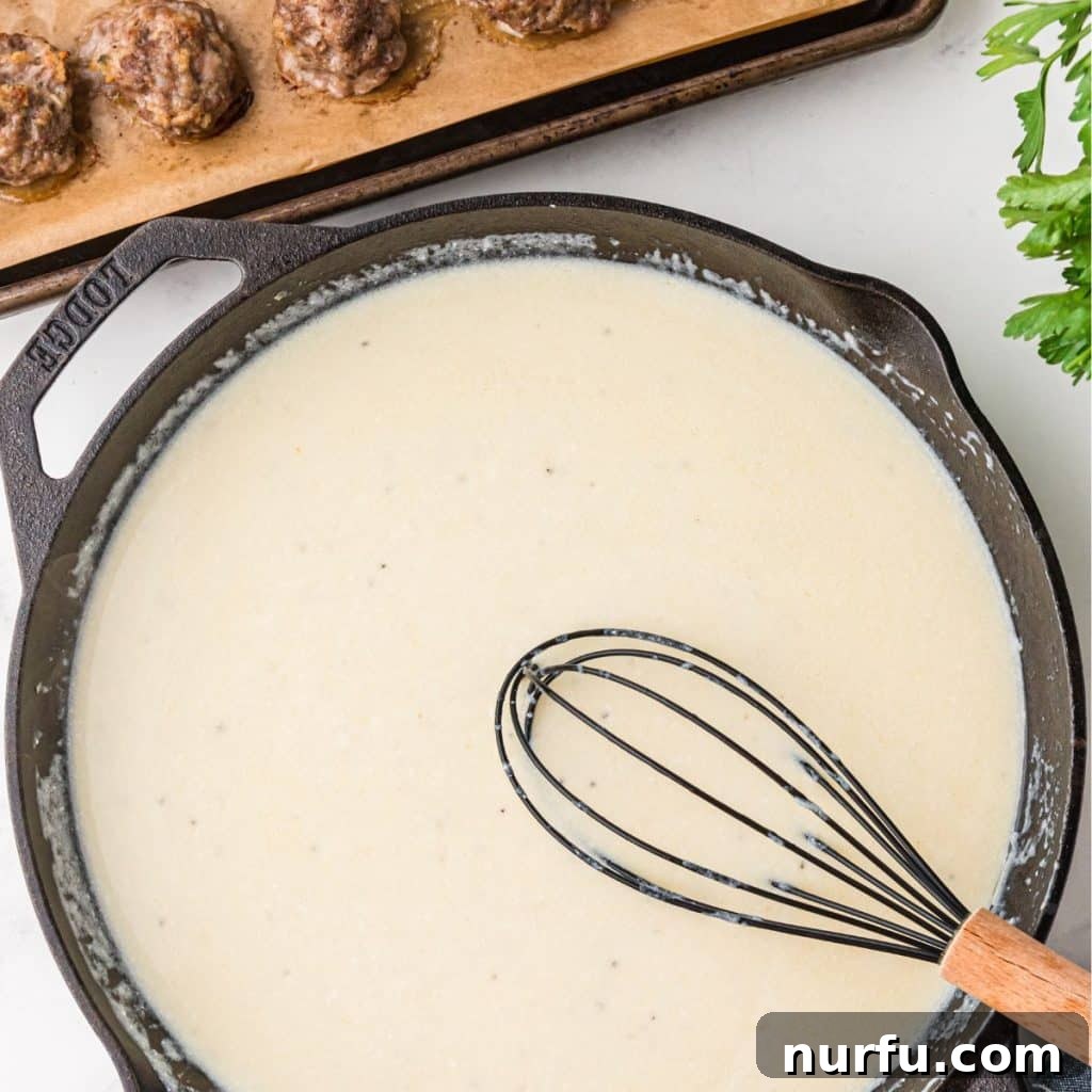 Irresistible Swedish Meatballs 6 Rich, creamy Swedish meatball sauce being whisked in a pan until smooth and thick.