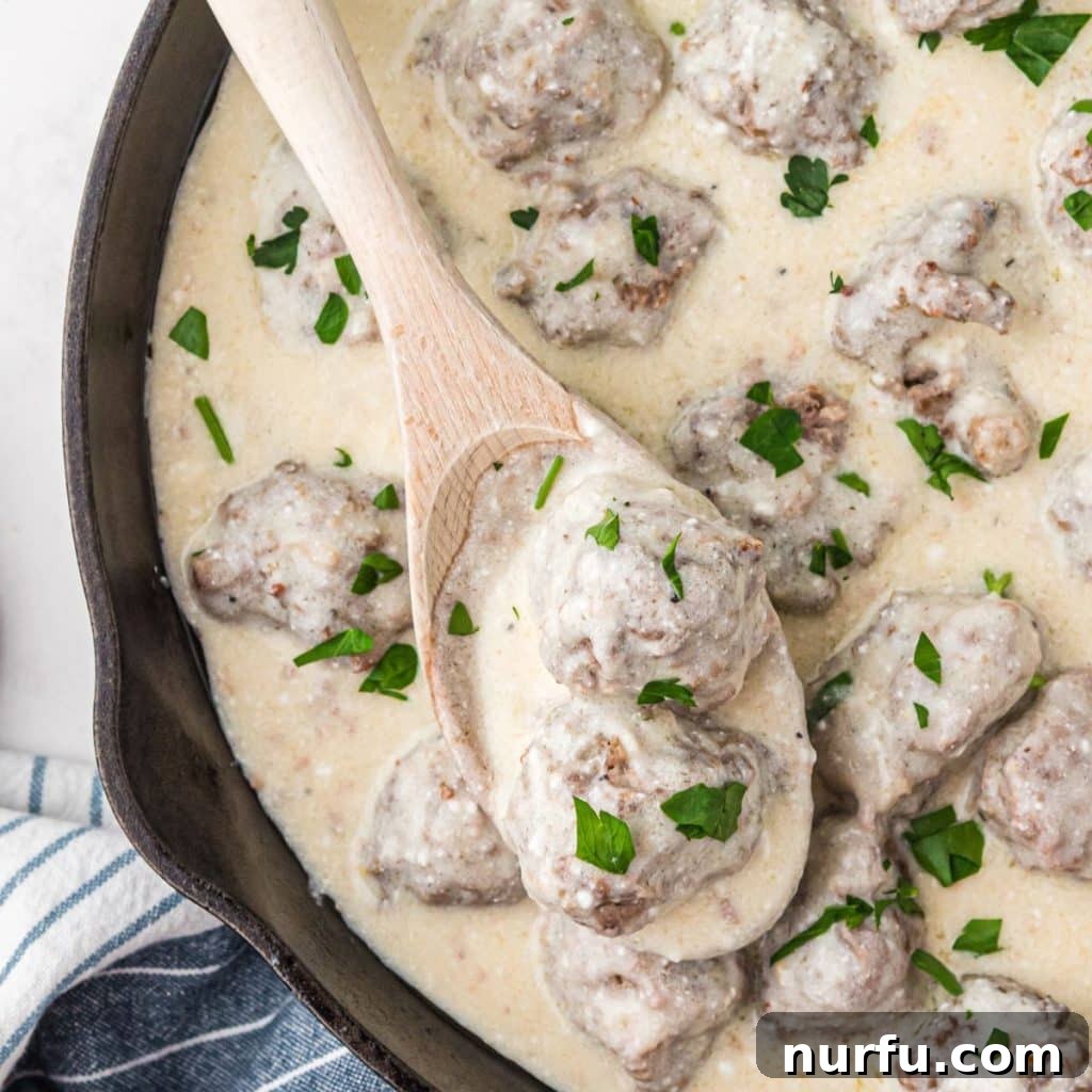 Irresistible Swedish Meatballs 7 Cast iron skillet filled with homemade Swedish meatballs in a rich, creamy sauce, garnished with fresh parsley.