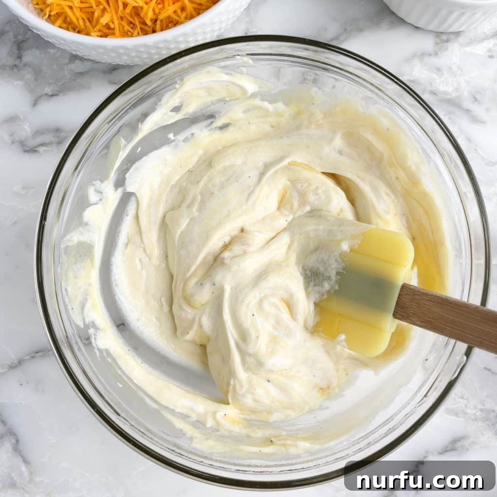 Flavorful Fiesta Spuds 4 Bowl with creamy sauce and a yellow spatula.