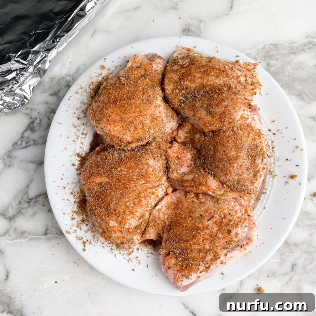 Get Juiciest Chicken Thighs The 350 Degree Bake Time Revealed 5 Plate of uncooked chicken thighs, fully seasoned and ready for baking.
