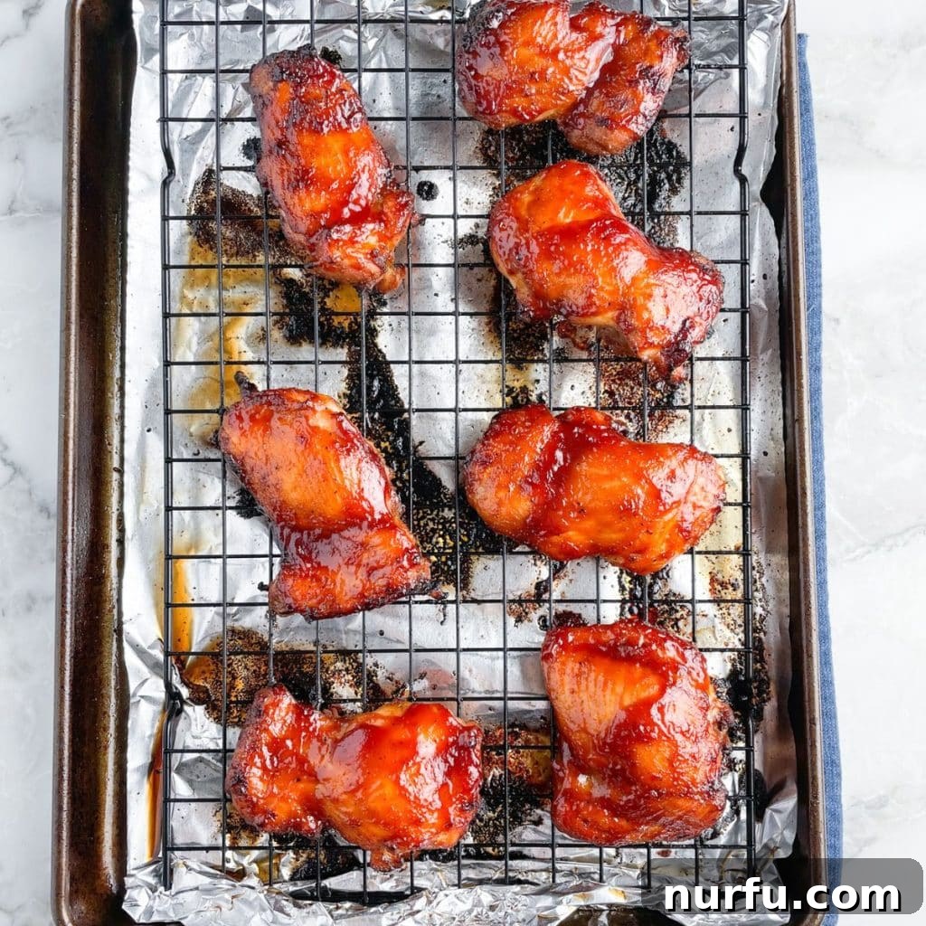 Sticky BBQ Chicken Thighs 7 A baking sheet filled with perfectly baked BBQ chicken thighs, glistening with sauce and ready to serve.