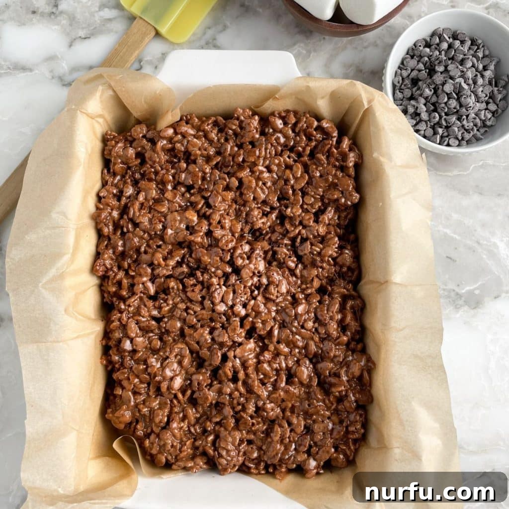 A baking dish filled with freshly made, dark chocolate Cocoa Krispie treats, ready to be cut into squares.