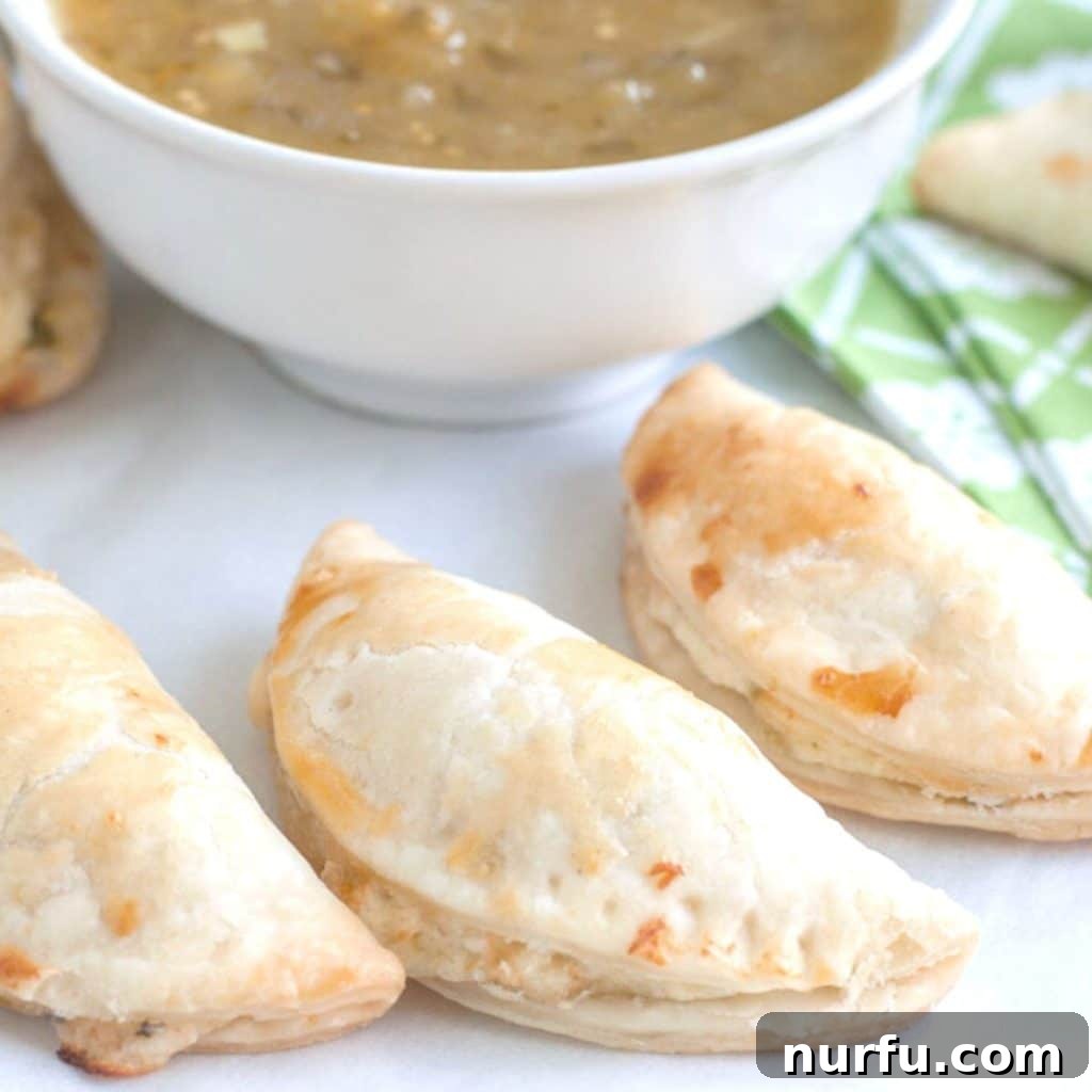 Empanadas served alongside a bowl of vibrant green salsa, indicating a Mexican-inspired dish.