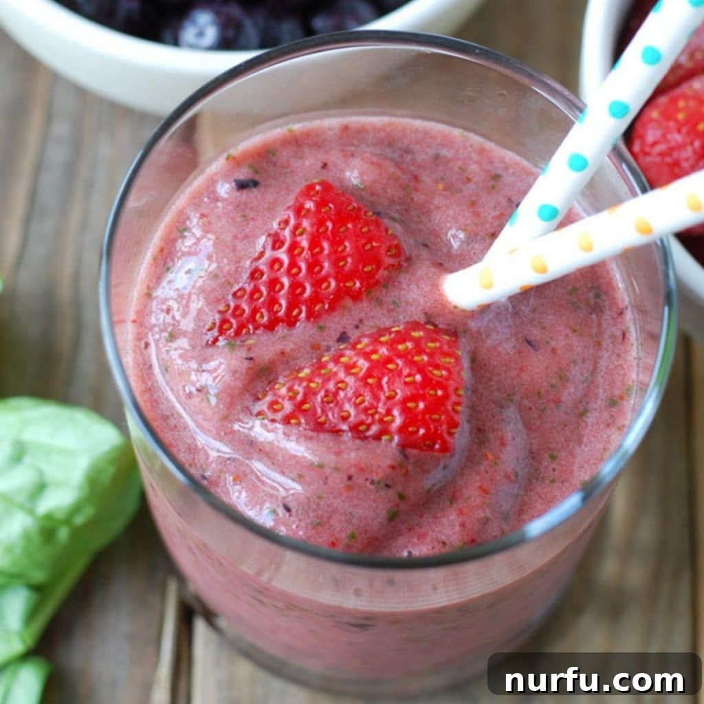 A vibrant berry smoothie in a glass, with fresh strawberries artfully arranged on the side, highlighting its freshness.