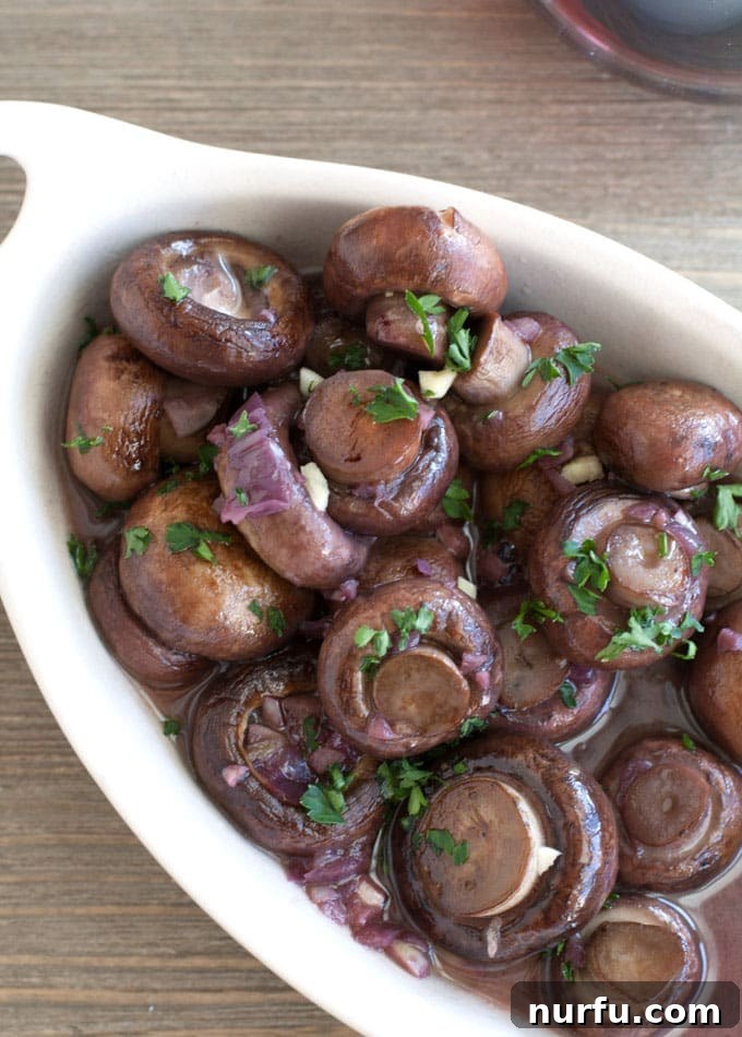 Bowl of red wine mushrooms, garnished with fresh herbs, ready to be served.