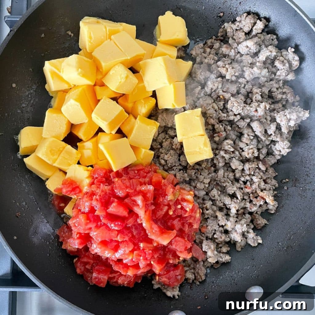 Creamy Velveeta Sausage Dip 5 Skillet with sausage, cubed Velveeta, and diced tomatoes.