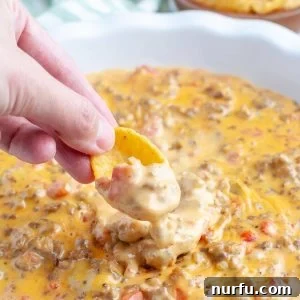Creamy Velveeta Sausage Dip 8 Hand holding ship with cheesy dip.