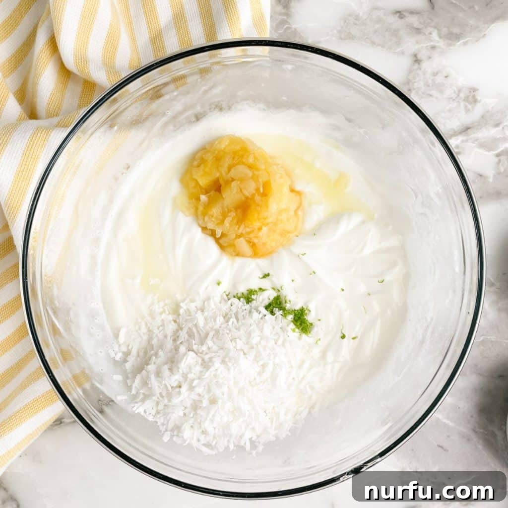 Bowl of creamy sauce with crushed pineapple, shredded coconut, and lime zest.