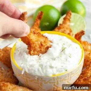 Coconut shrimp dipping in a bowl of creamy sauce.