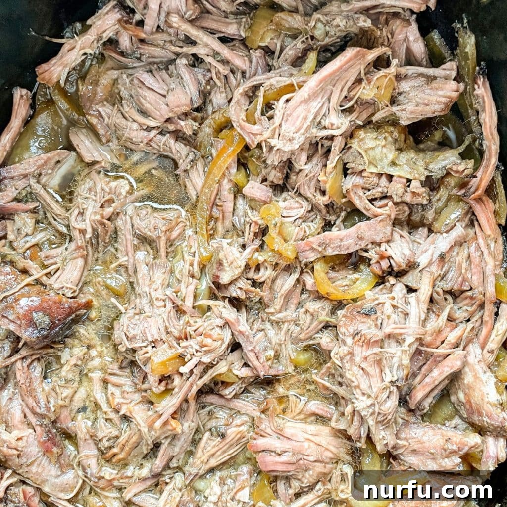 Melt-in-Your-Mouth Slow Cooker Beef 6 Close-up of fully cooked, perfectly shredded beef still in the slow cooker, swimming in its flavorful cooking juices, ready to be served.