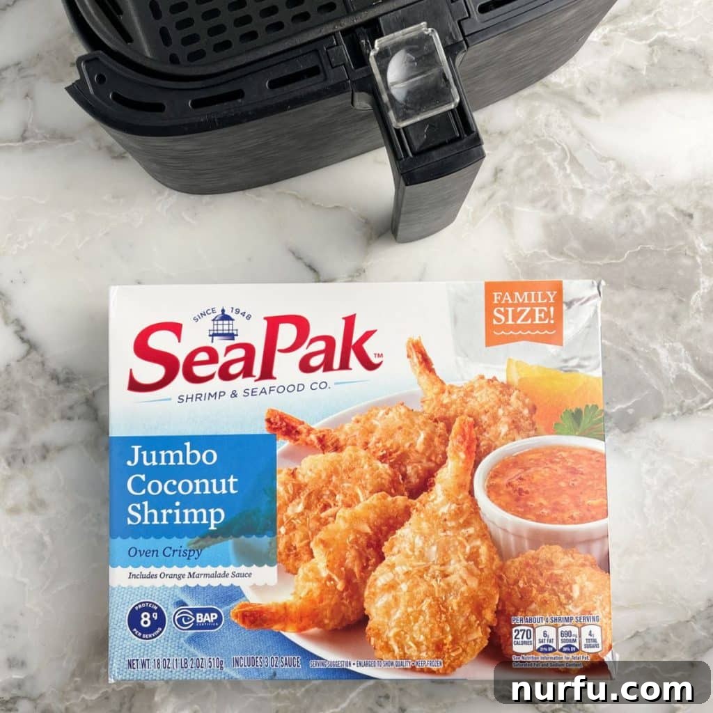 Crispy Air Fryer Frozen Coconut Shrimp 3 A box of frozen coconut shrimp next to an empty air fryer basket, illustrating the simple ingredients needed.