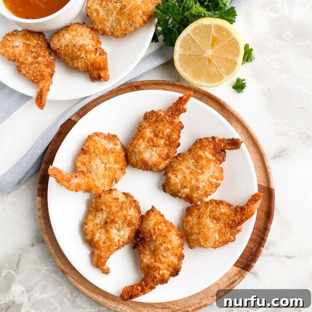 Crispy Air Fryer Frozen Coconut Shrimp 5 A beautifully arranged plate of crispy air-fried coconut shrimp, garnished and ready for serving.
