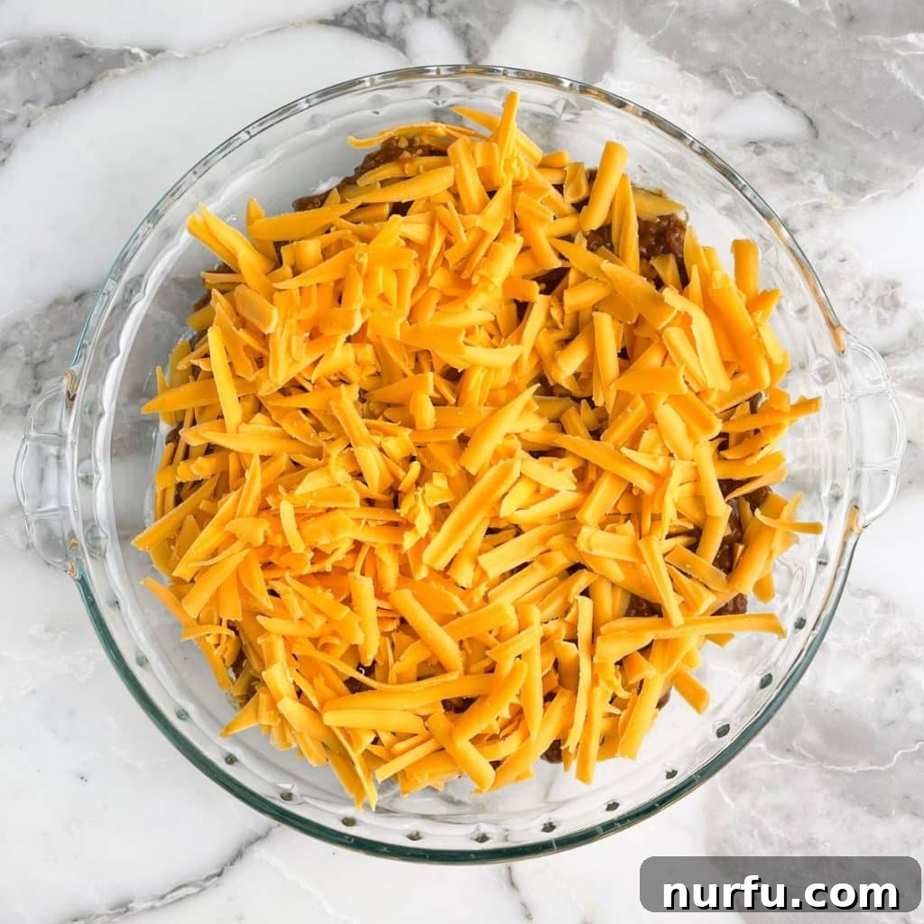 Spicy Cheese Dream 6 Shredded cheese on top of chili in a pie plate.