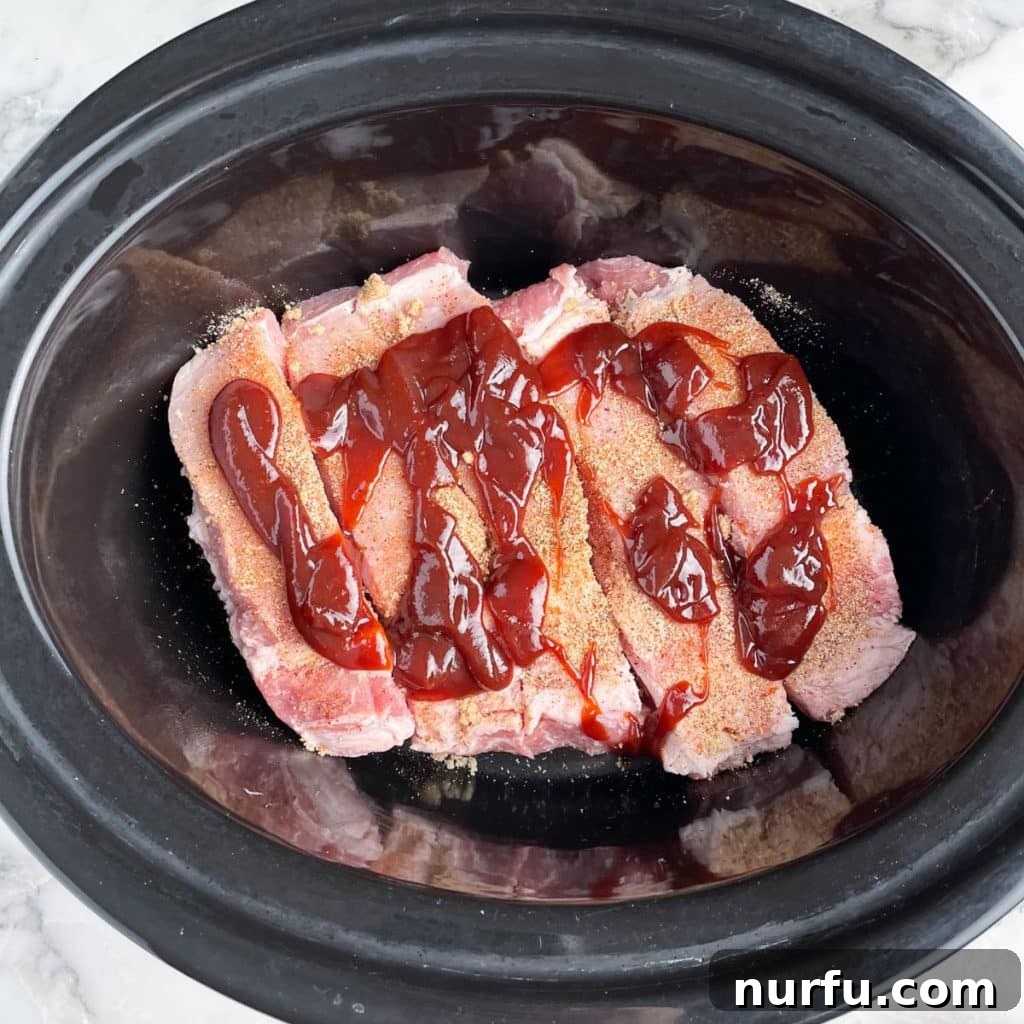 Tender Slow Cooker Country Ribs 5 Slow cooker filled with country style ribs and BBQ sauce, ready for cooking.
