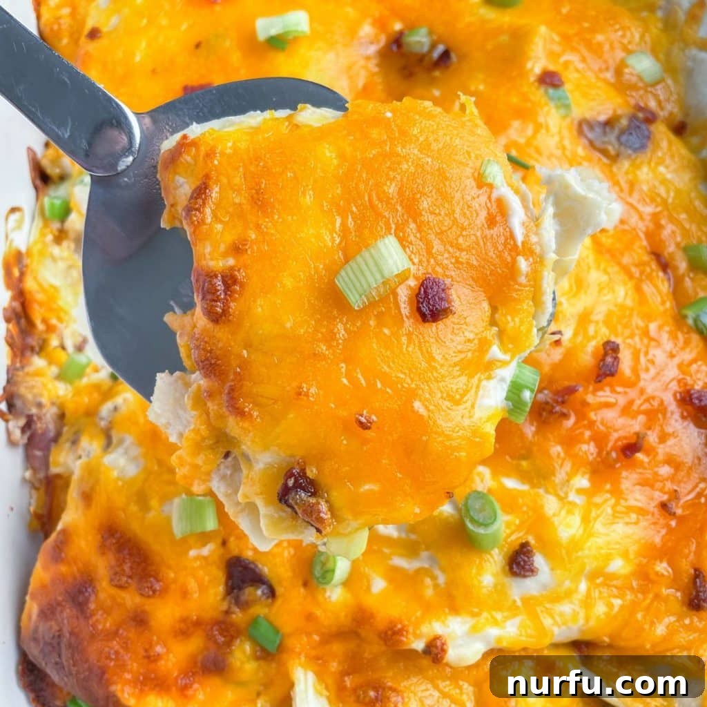 Comforting Pierogi Bake 2 A spatula lifting a cheesy portion of pierogi casserole from a baking dish, highlighting the melted cheese and tender pierogies.