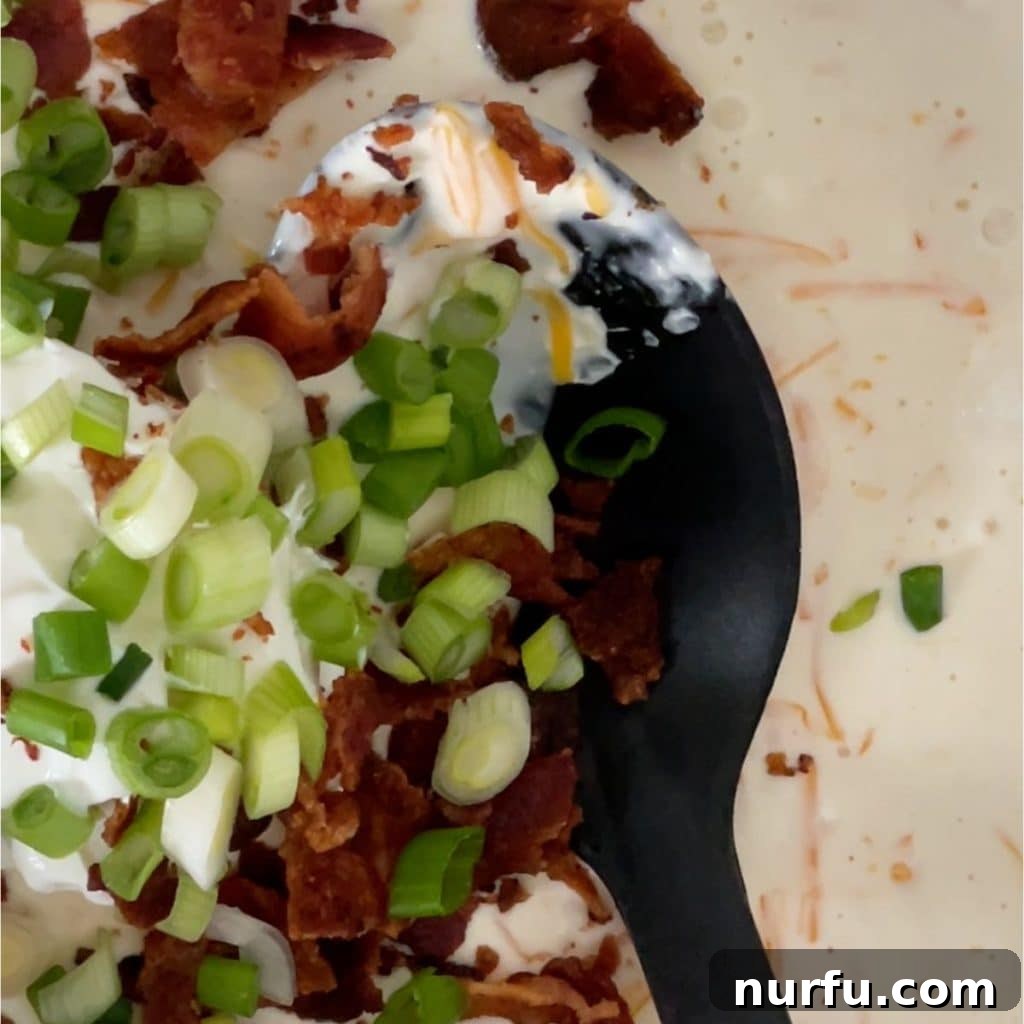 Comforting Pierogi Bake 5 A spoonful of creamy white sauce with green onions and bacon bits, ready to be mixed into a dish.