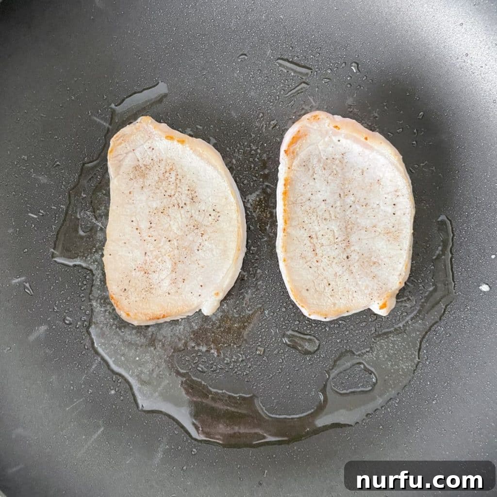 Perfectly seared thin pork chops cooking in a skillet, showcasing a magnificent golden crust on both sides and indicating they are precisely ready for a final temperature check.