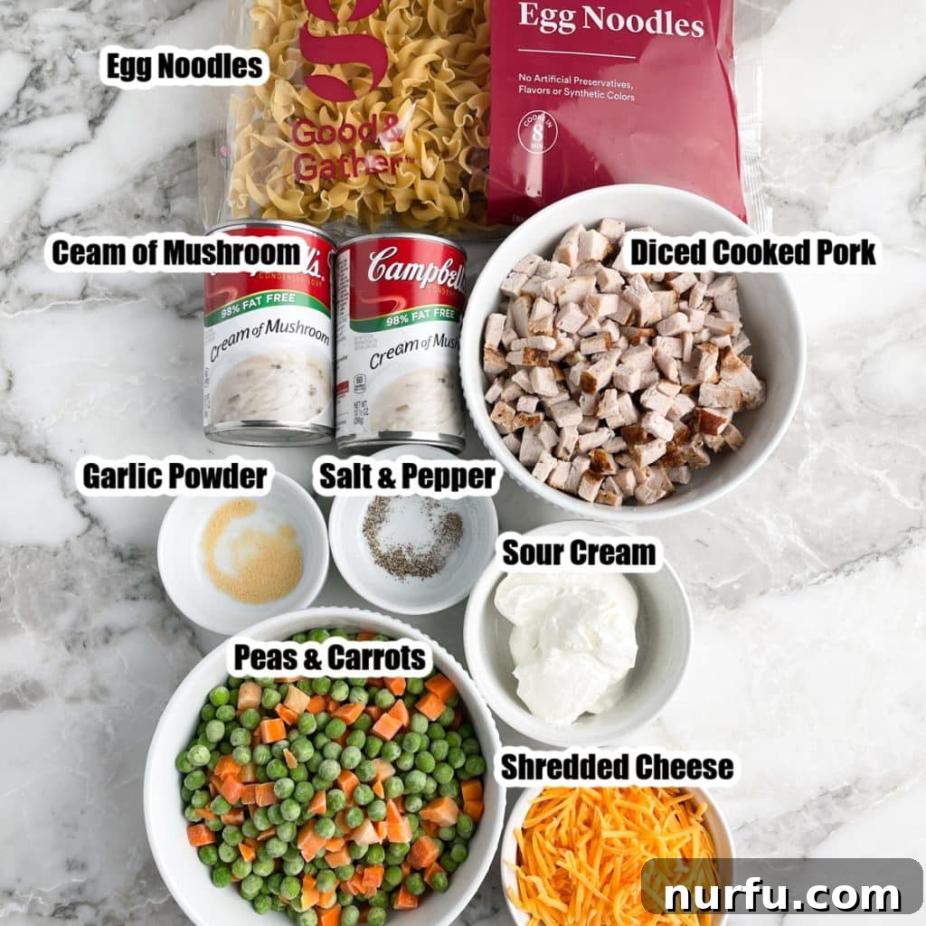Hearty Pork Casserole 3 Individual ingredients for pork casserole laid out: egg noodles, diced pork, peas and carrots, sour cream, shredded cheese, and cans of cream of mushroom soup.