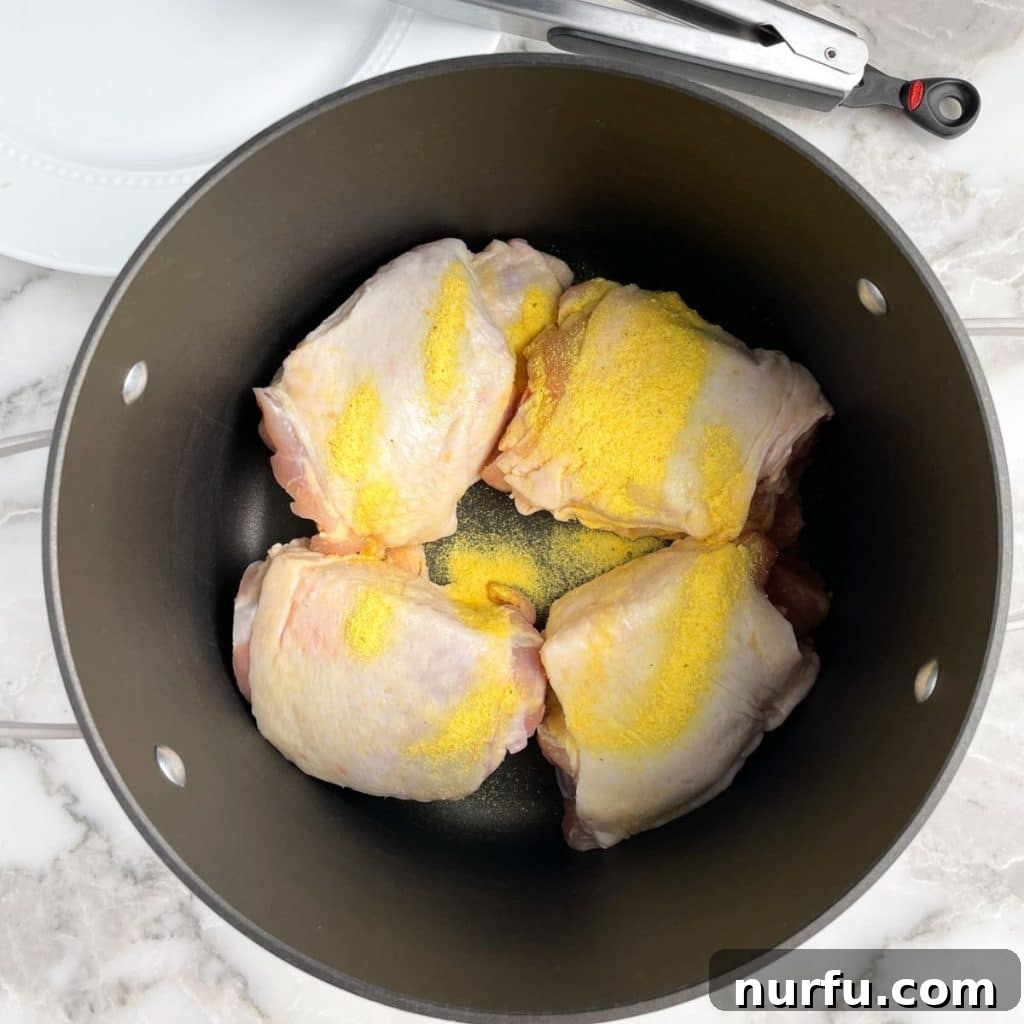 The Secret to Perfectly Tender Boiled Chicken Thighs 4 Pot containing chicken thighs seasoned with bouillon before adding water.