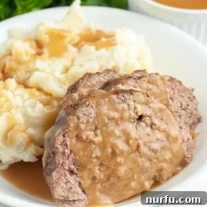Meatloaf with gravy and mashed potatoes on a plate.