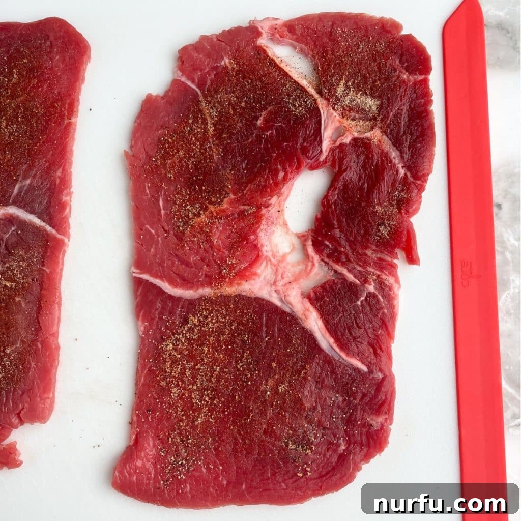 Uncooked sizzle steak generously coated with a savory spice blend, ready for the pan.