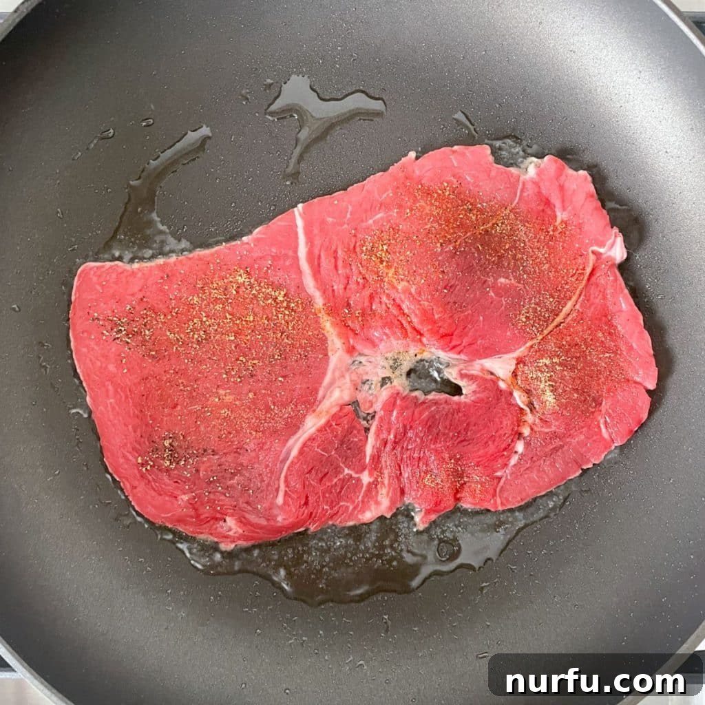 Sizzle steak searing in a hot skillet, developing a delicious brown crust.