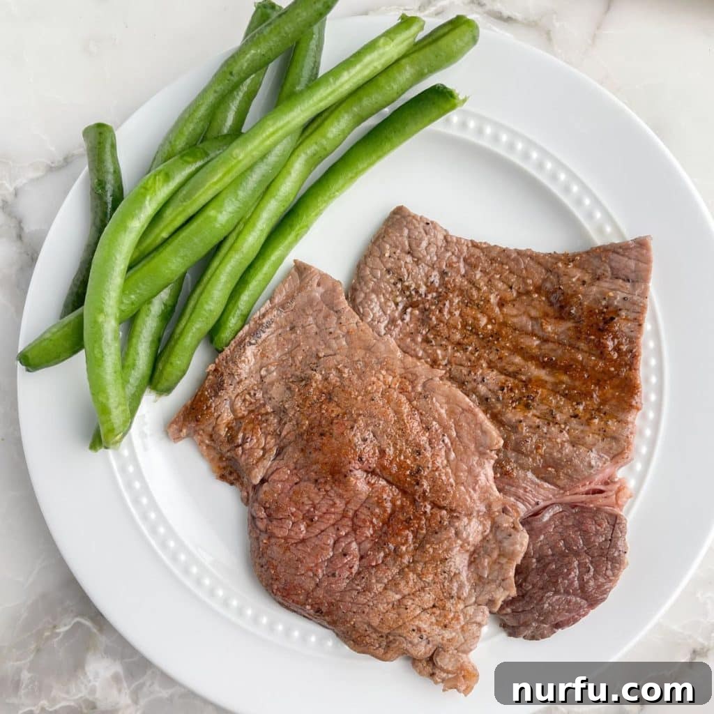 A beautiful plate of cooked sizzle steak with vibrant green beans, showcasing its tender, juicy perfection.