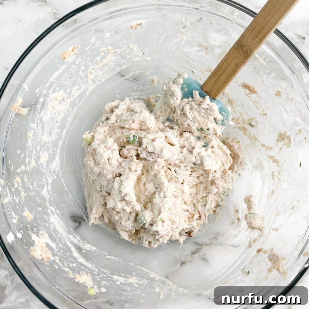 Bowl of salmon salad with a spatula, indicating it's ready for serving or transferring.