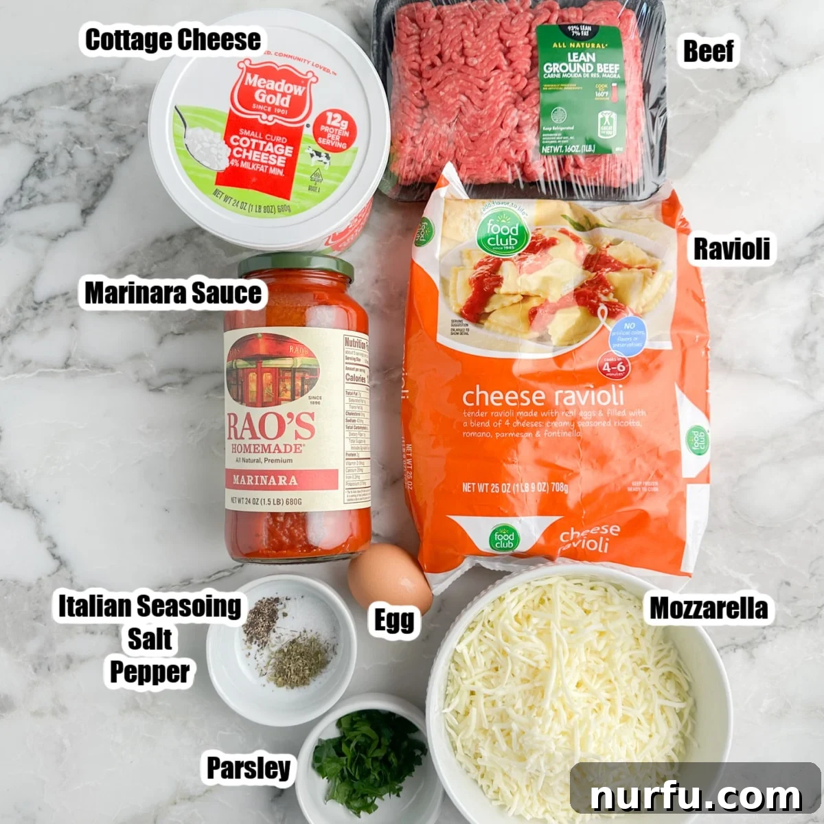 Hearty Ravioli Lasagna Bake 3 A flat lay of fresh ingredients including a bag of ravioli, cottage cheese, marinara sauce, shredded mozzarella, ground beef, and various seasonings, all prepared and ready for assembly.