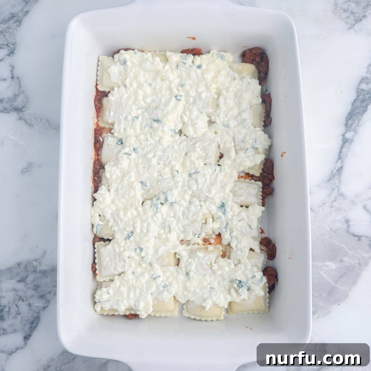 Hearty Ravioli Lasagna Bake 6 The creamy cottage cheese mixture, flecked with green parsley, spread smoothly over the layer of ravioli in the baking dish.