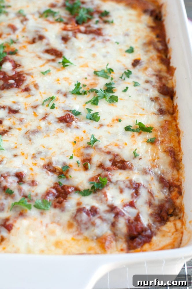 Hearty Ravioli Lasagna Bake 8 A freshly baked, golden-brown Baked Ravioli Lasagna in a white casserole dish, garnished with vibrant fresh herbs, ready to be served.