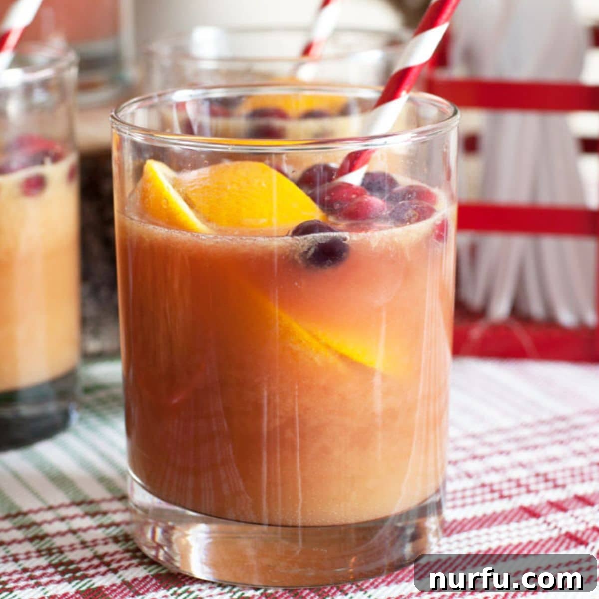 Virgin Holiday Punch 2 A beautifully garnished glass of festive holiday punch, featuring a slice of orange and a straw, ready for sipping.