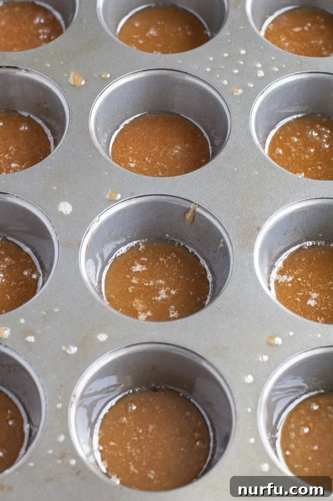 Tangy Cranberry Orange Mini Upside-Downs 2 Muffin tin with melted butter and brown sugar in each cup, ready for cranberries and cake batter.