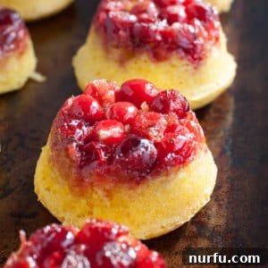 Mini cranberry upside down cakes on a pan, showcasing their vibrant red berries and golden cake.