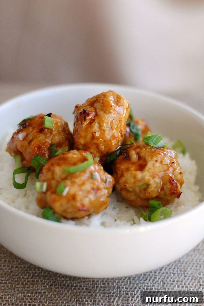 Golden Glazed Honey Garlic Turmeric Chicken 8 Savory chicken meatballs served over a bed of fluffy white rice in a bowl, garnished and ready to eat.