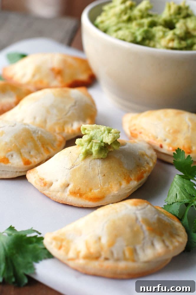 Golden Glazed Honey Garlic Turmeric Chicken 4 Small, golden-brown chicken empanadas served with a dollop of fresh guacamole, perfect as an appetizer or light meal.