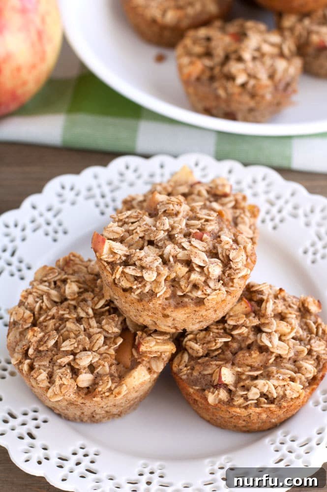 apple cinnamon baked oatmeal cups A plate of stacked baked apple cinnamon oatmeal cups, ready for serving or meal prepping.