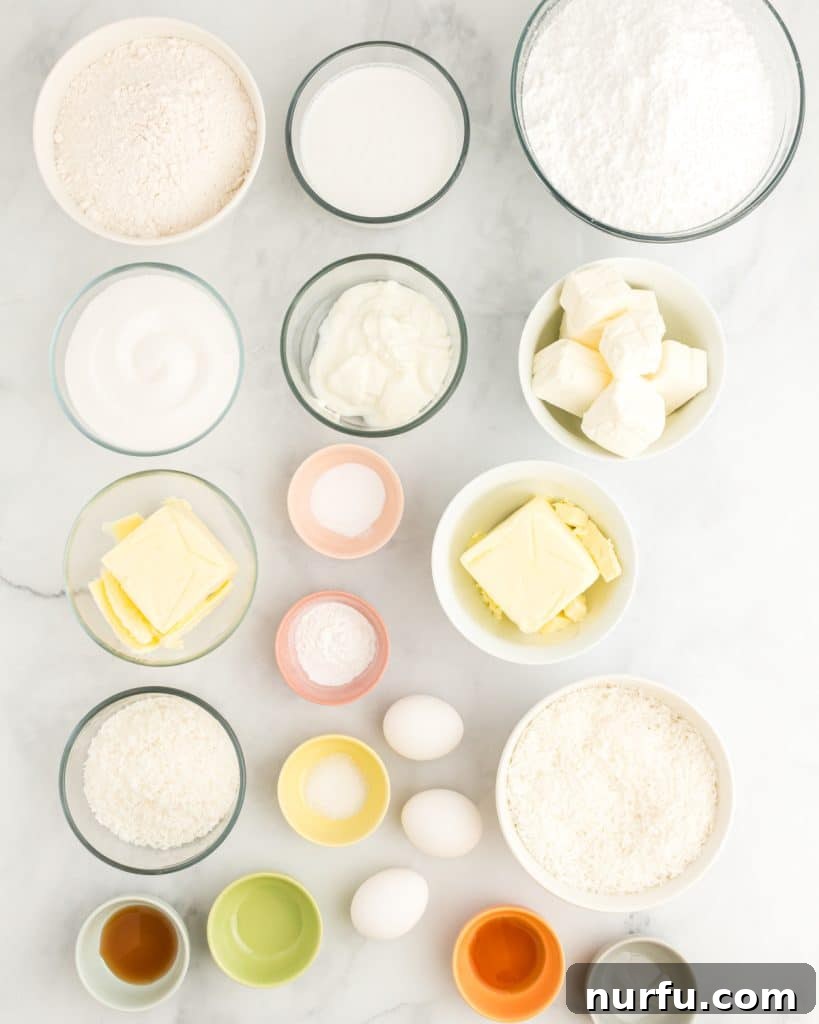 Tropical Coconut Dream Cake 3 A collection of baking essentials laid out, including bowls of flour, sugar, cream cheese, alongside vanilla extract, butter, and coconut extract, all ready for making a delicious coconut sheet cake.