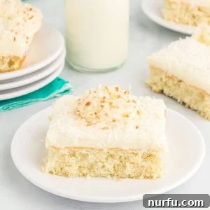 Tropical Coconut Dream Cake 8 A delicious slice of coconut sheet cake on a plate, featuring fluffy cream cheese frosting and toasted coconut.