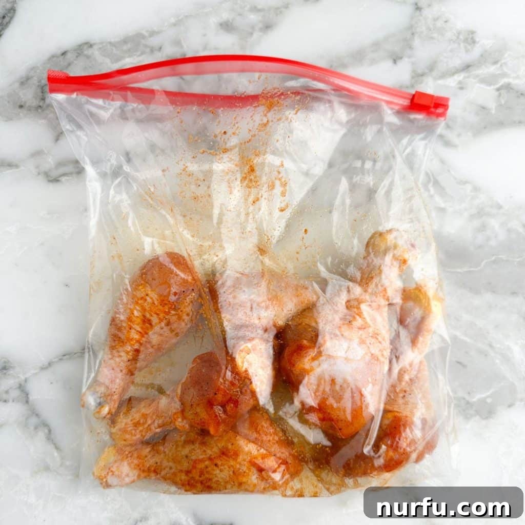Baked Chicken Drumsticks: The Perfect Cooking Time 5 Chicken legs coated in seasonings inside a zip-top bag, ready for baking.