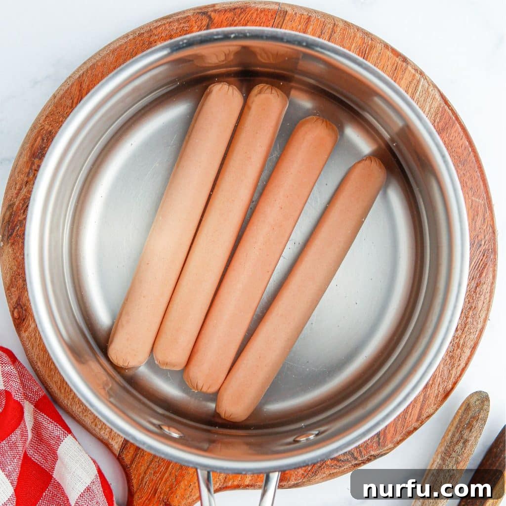 Mastering the Authentic Chicago Hot Dog 4 Hot dogs simmering in a pot of boiling water, the traditional method for preparing Chicago style hot dogs, ensuring they are perfectly cooked and juicy.